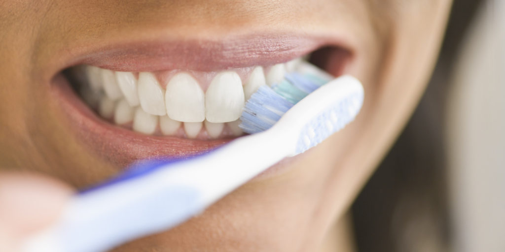 Close up of person brushing teeth often and regularly.